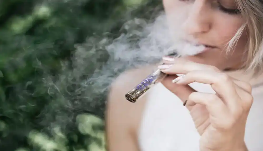 A blonde woman smoking from her vape filled with cannabis terpene