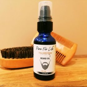 awesome hemp beard oil sitting on a wooden table nest to a brush