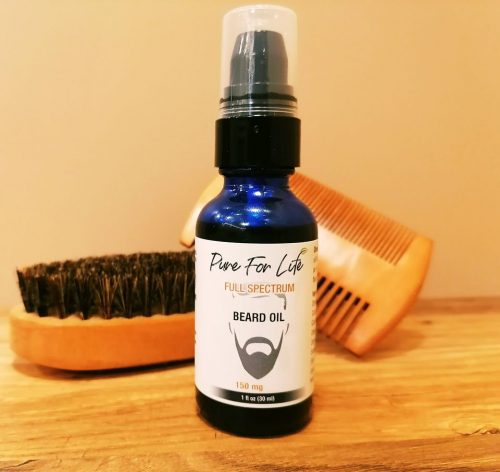 awesome hemp beard oil sitting on a wooden table nest to a brush