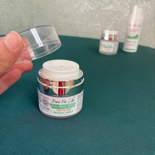 Cream for pain relief from THC and CBD sitting on a table with open cap