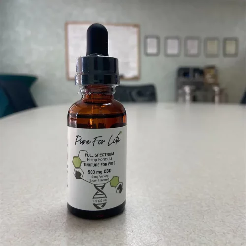 a bottle with cannabidiol tincture for pets sitting on a white table
