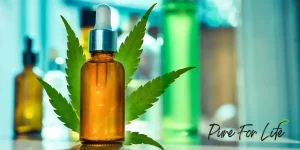 A bottle with CBD in front of a cannabis leaf and other blurry bottles on background