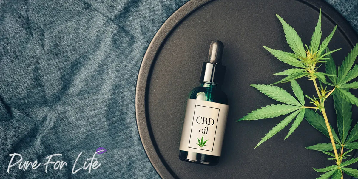 A bottle with CBD on a plate and cannabis leaf next to it